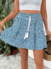 Front view of floral print blue mini skirt with tassel tie on model – Voguelle