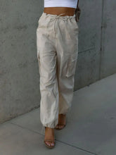 Front view of beige cargo trousers with functional side pockets – Voguelle