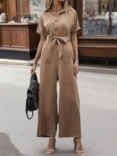 Front view of short sleeve wide-leg jumpsuit in brown with belt on model – Voguelle
