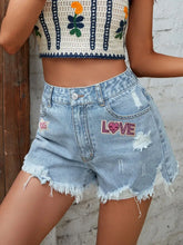 Front view of light wash distressed raw hem denim shorts with LOVE patch – Voguelle
