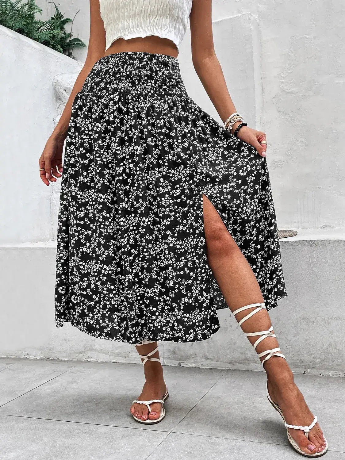 Front view of high waist smocked printed black skirt with slit on model – Voguelle
