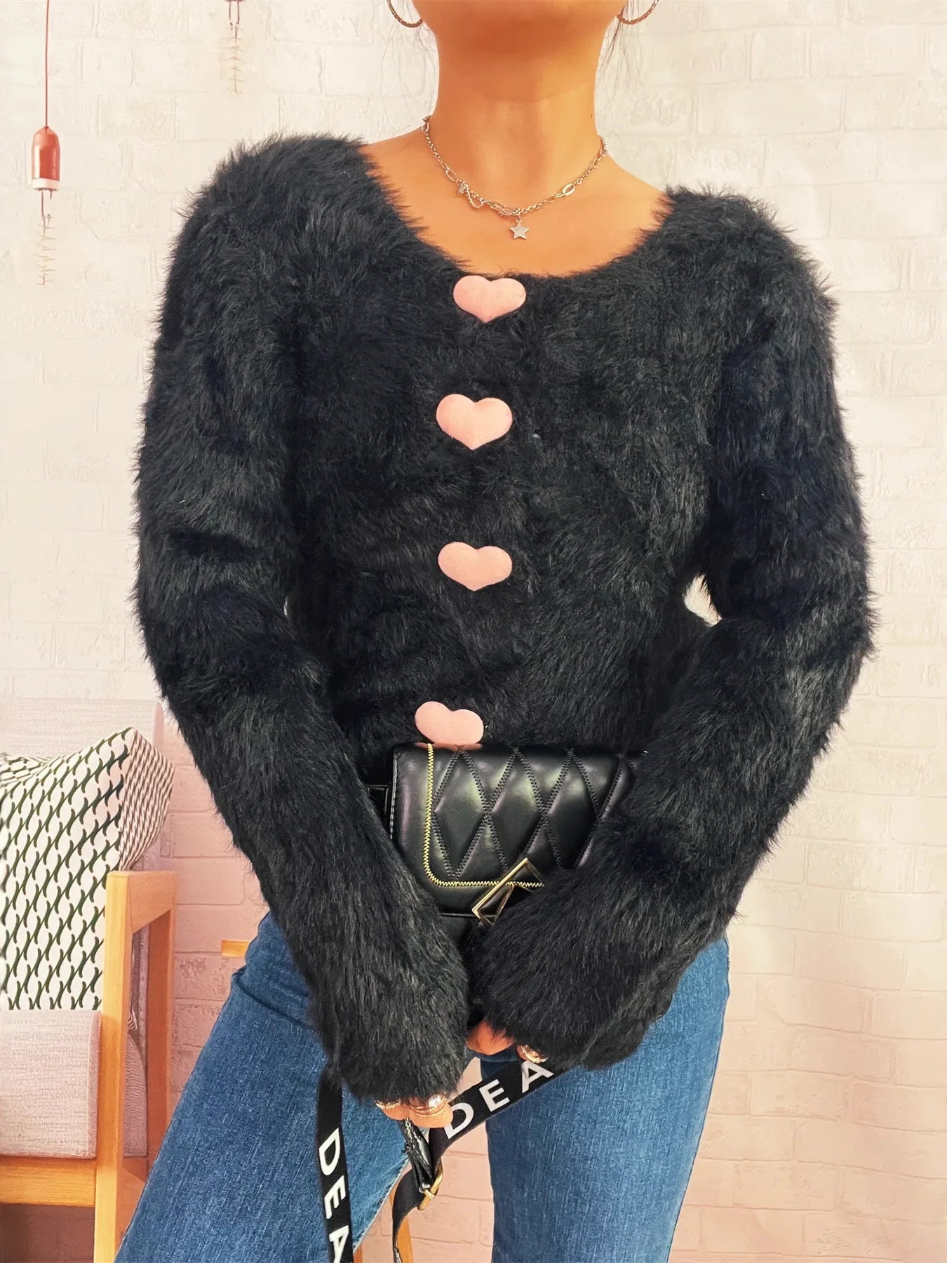 Cropped detail of black fuzzy cardigan with pink buttons – Voguelle