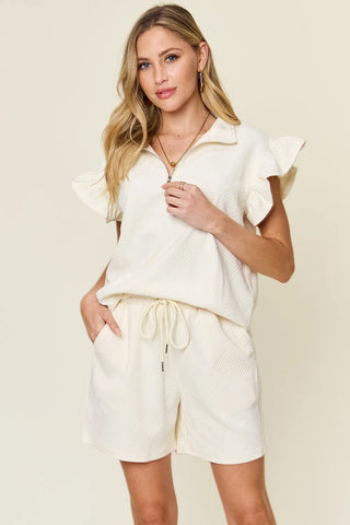 Model posing in cream drawstring shorts and flounce sleeve top – Voguelle