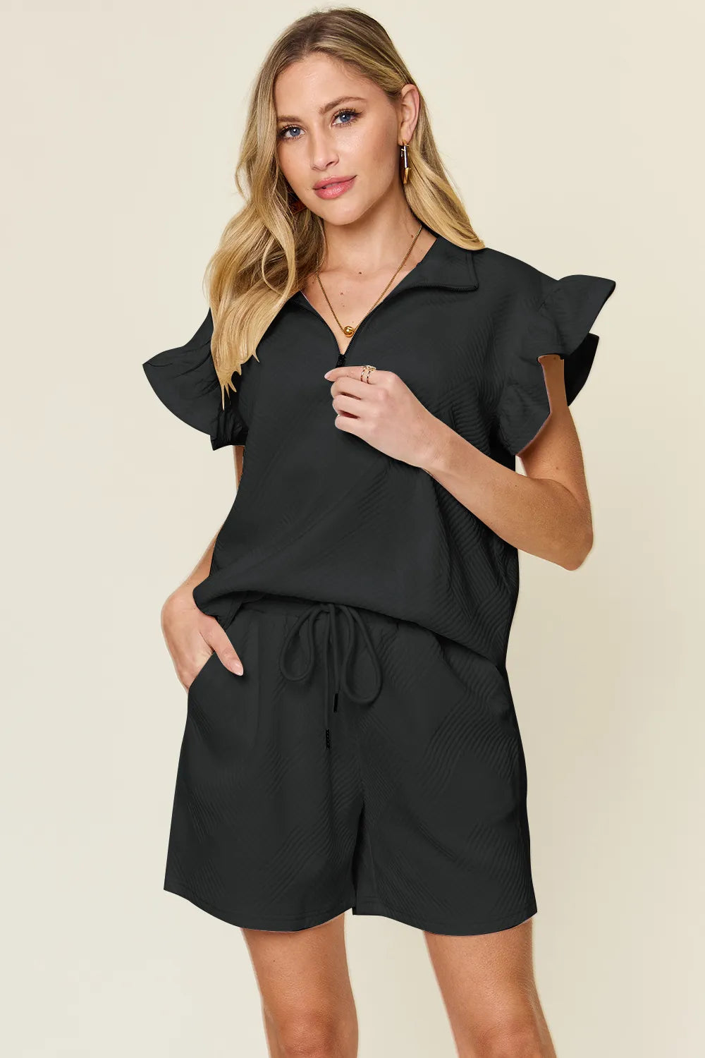 Model posing in cream drawstring shorts and flounce sleeve top – Voguelle