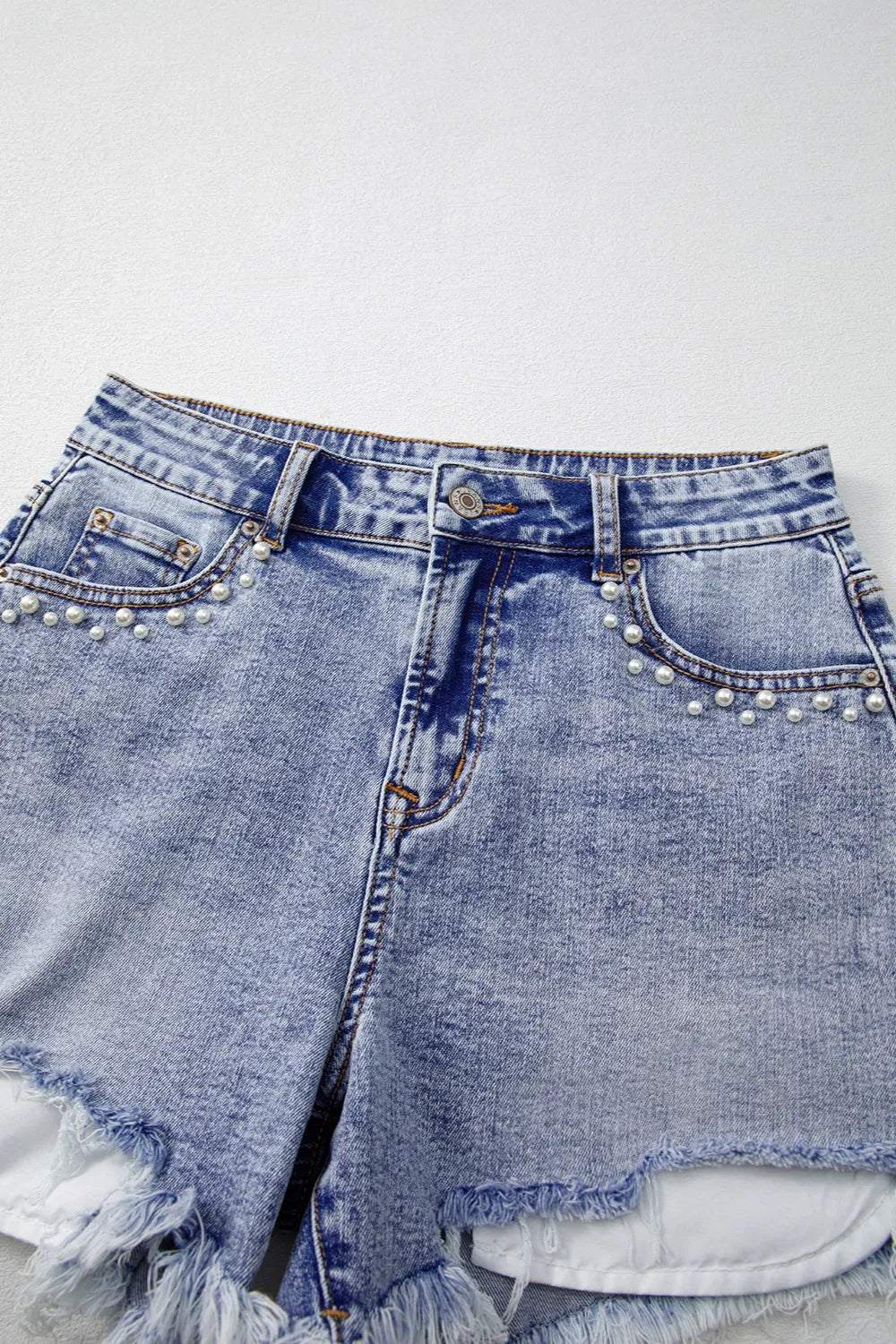 Close-up of raw hem edge on pearl studded denim shorts – Voguelle