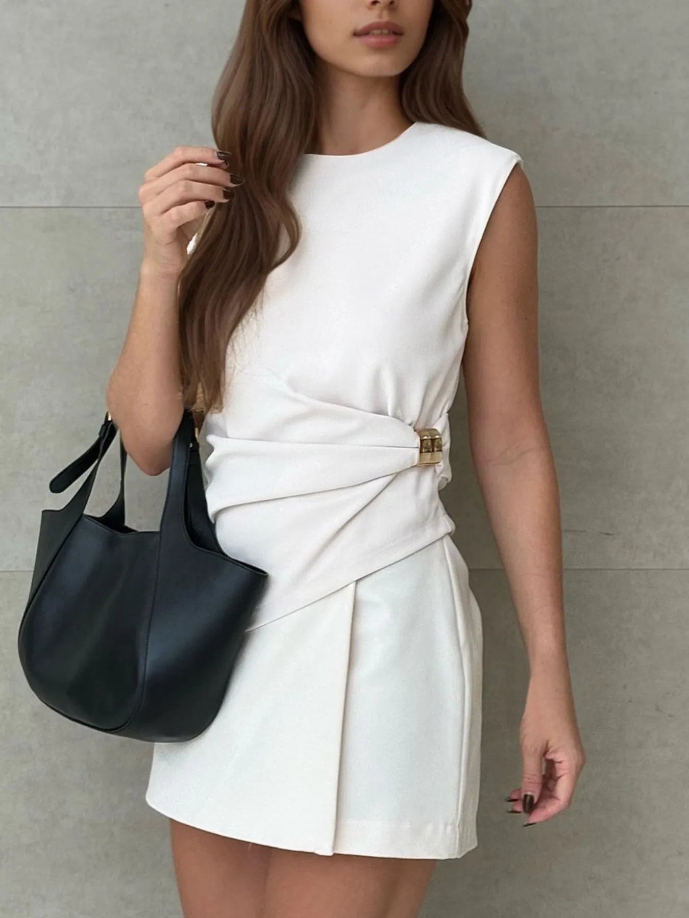 Close-up of round neck sleeveless white dress styled with black handbag – Voguelle