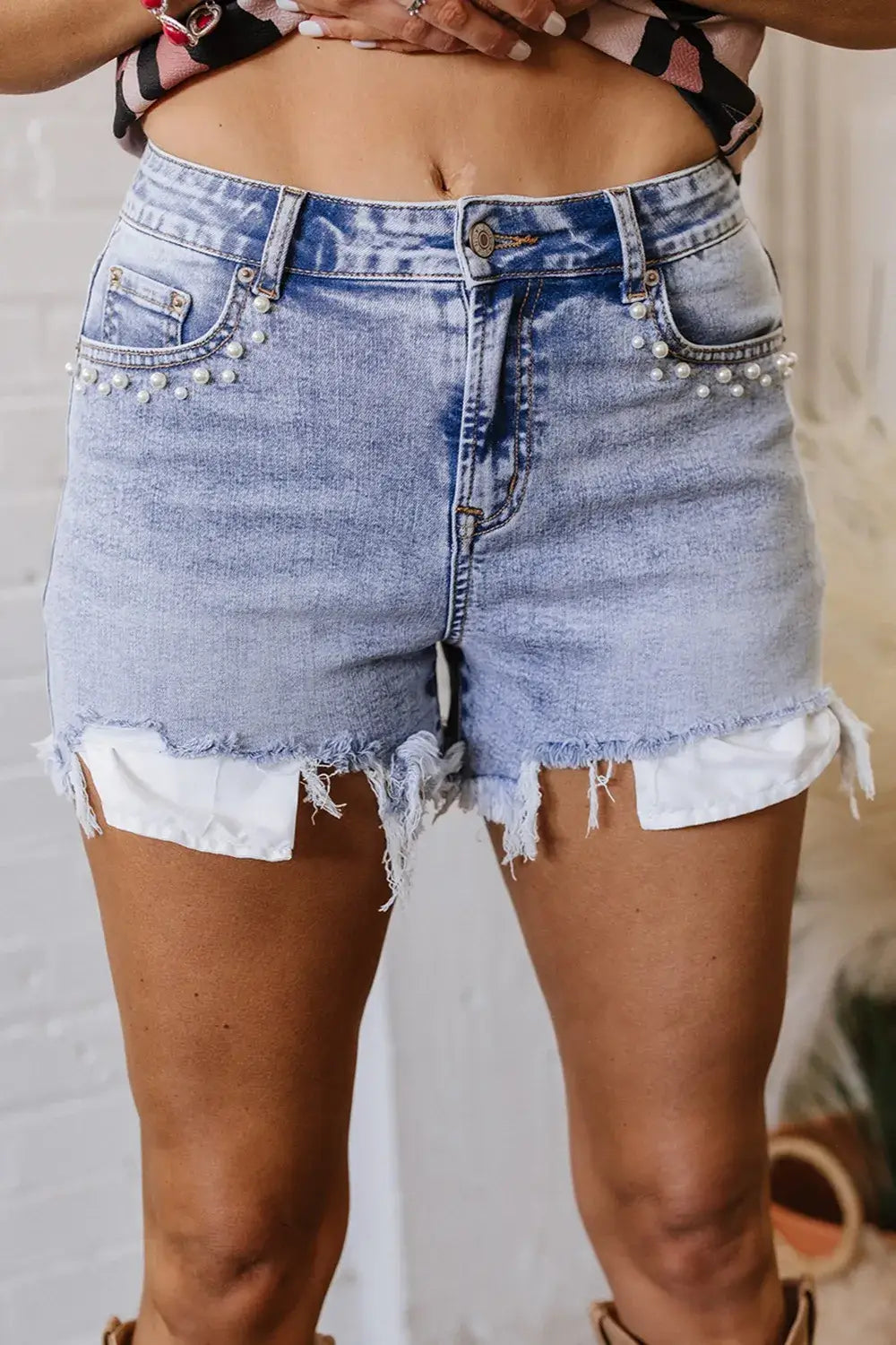 Front view of women’s pearl studded raw hem denim shorts – Voguelle