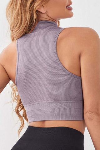 Back view of a model wearing a mock neck ribbed sports tank in soft gray, showcasing its stylish design and drawstring feature.