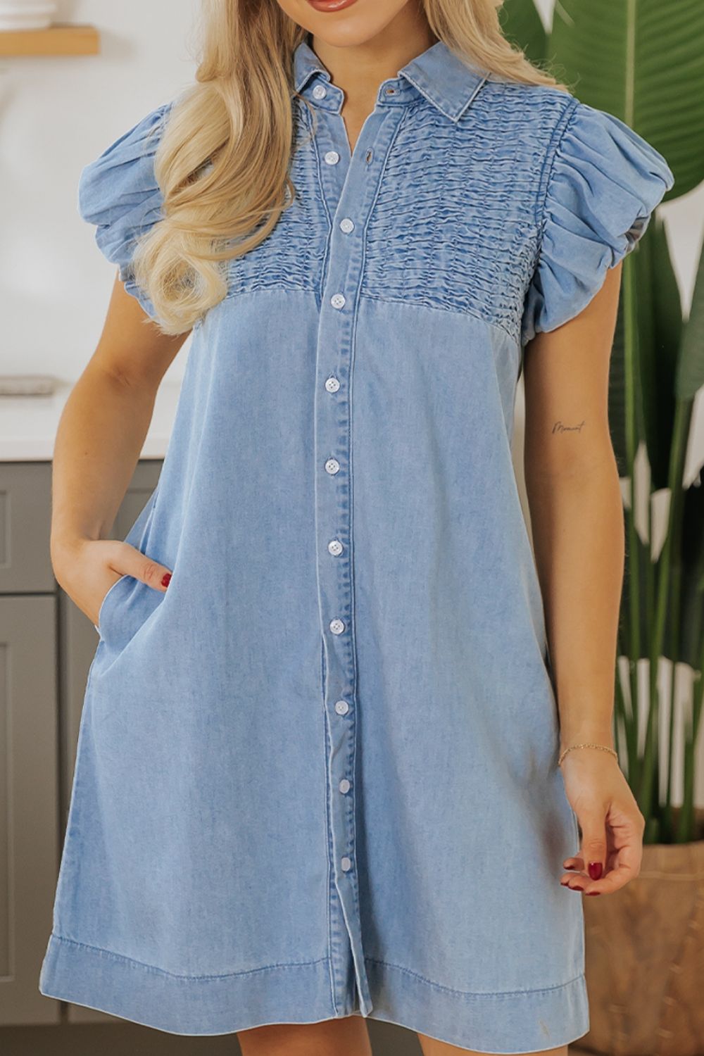 Model wearing sleeveless smocked denim dress with cap sleeves – Voguelle